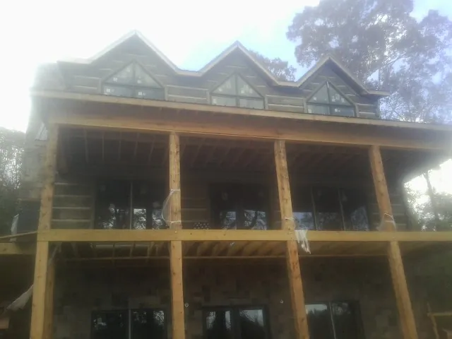 Dormers and porch framing on a large log home under construction — Roof Coating work by our crew in Wallops Island