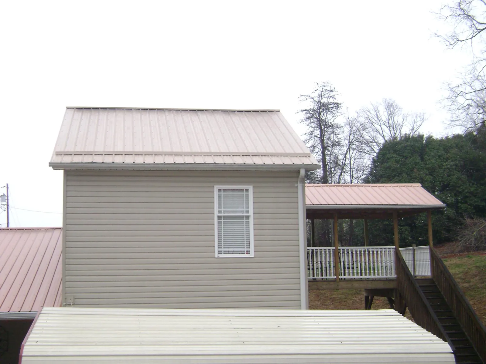 Tan metal roofs on a two story addition and attached porch, from a Roof Replacement job in Wallops Island