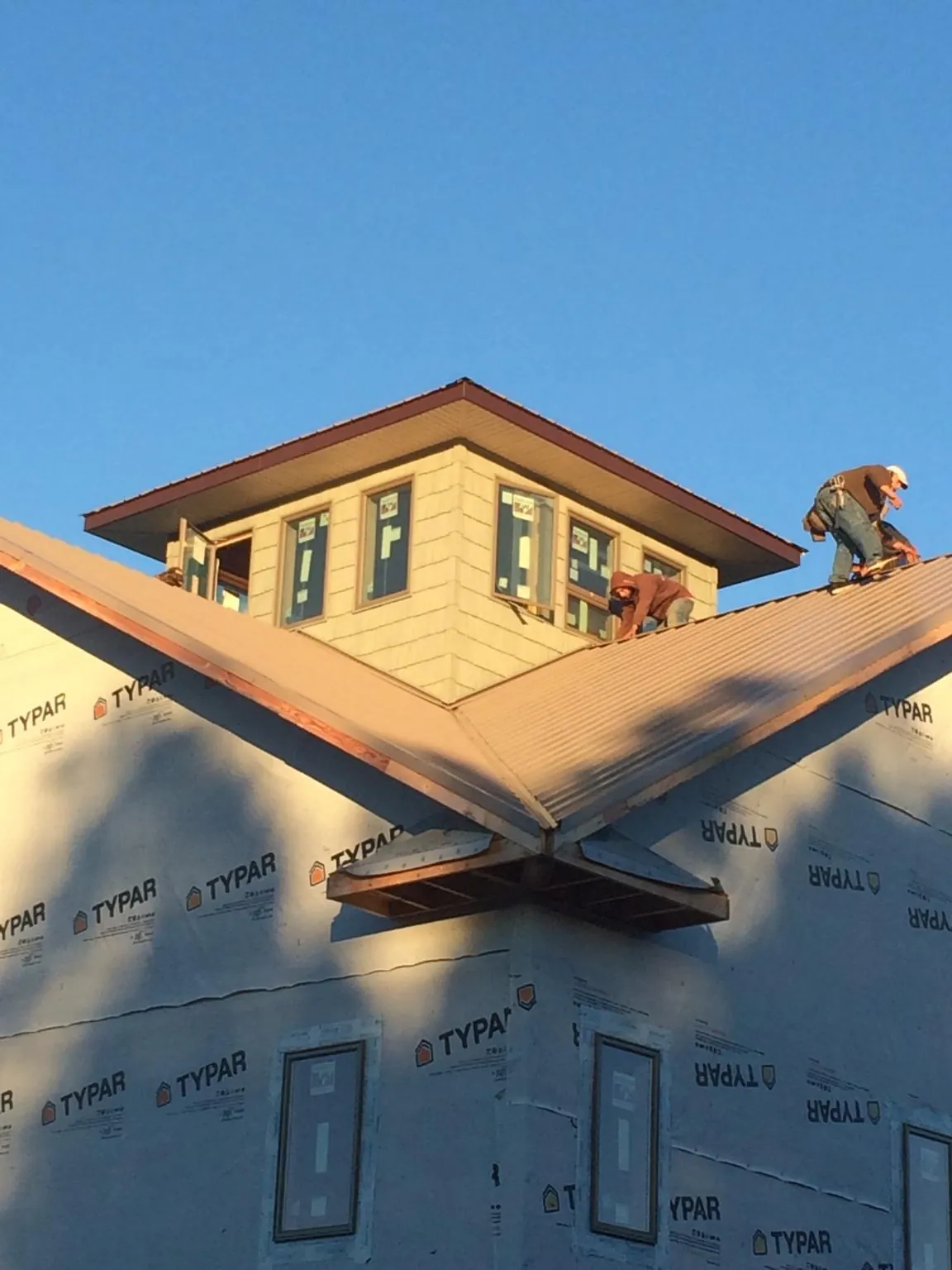 Roofers working around a rooftop cupola on a new metal roof at sunset — Roof Waterproofing in Wallops Island by Roofing Brothers
